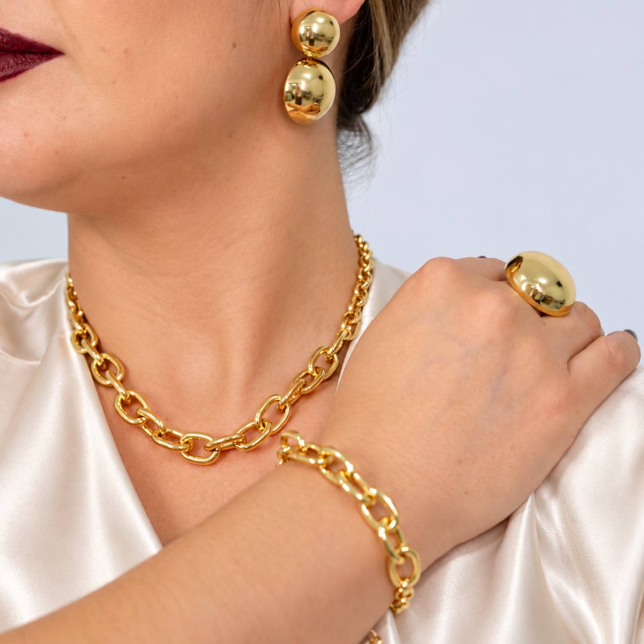 Mulher usando brincos, colar, pulseira e anel dourados