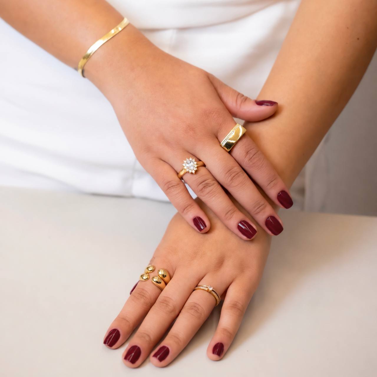 Mãos usando diferentes anéis e pulseiras douradas
